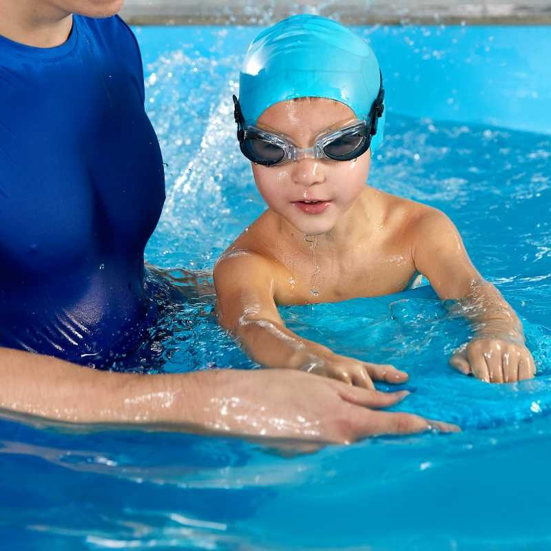 instructor with kid in swimming pool giving a lesson